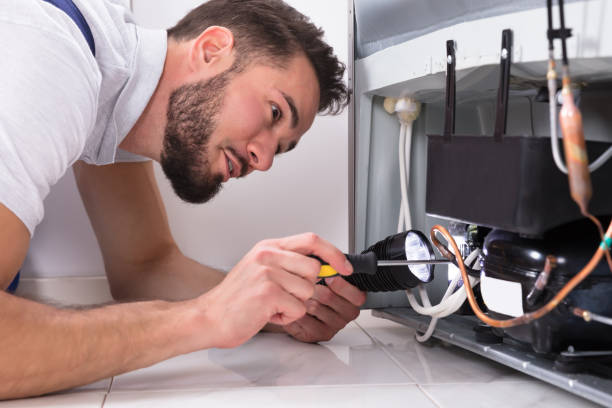 Photo Of Male Technician Repairing Refrigerator With Screwdriver Photo Of Male Technician Repairing Refrigerator With Screwdriver
